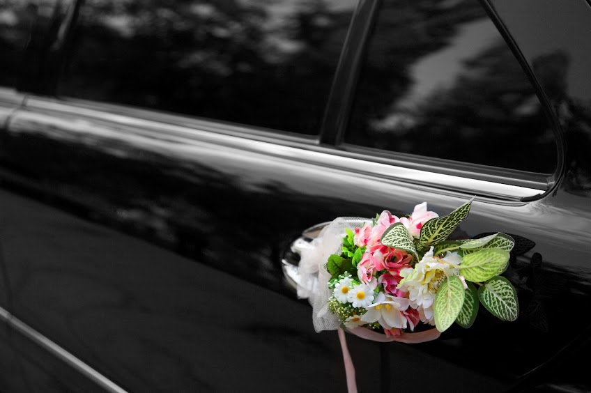 Door of black wedding car with flowers